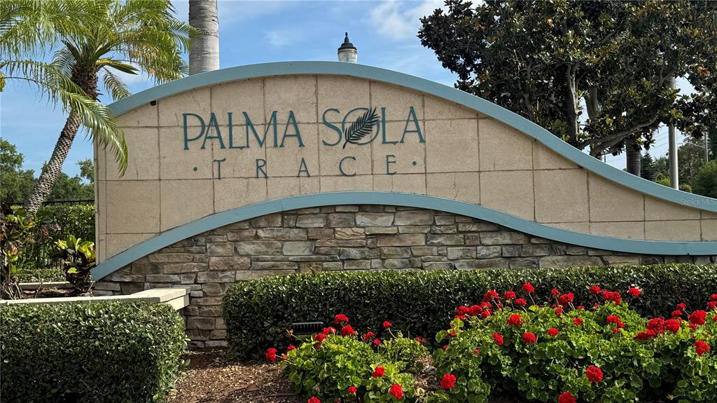 A stone and stucco monument sign for Palma Sola Trace sits behind a flower bed — 7338 SKYBIRD ROAD UNIT 413, BRADENTON, FL