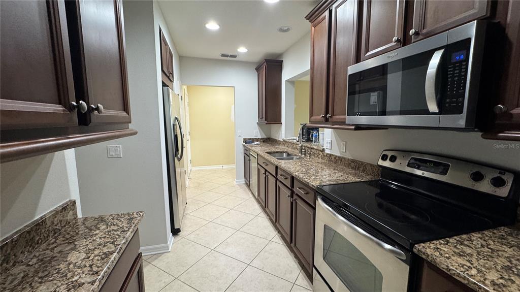 A kitchen features dark wood cabinets, granite countertops, and stainless steel appliances — 7338 SKYBIRD ROAD UNIT 413, BRADENTON, FL