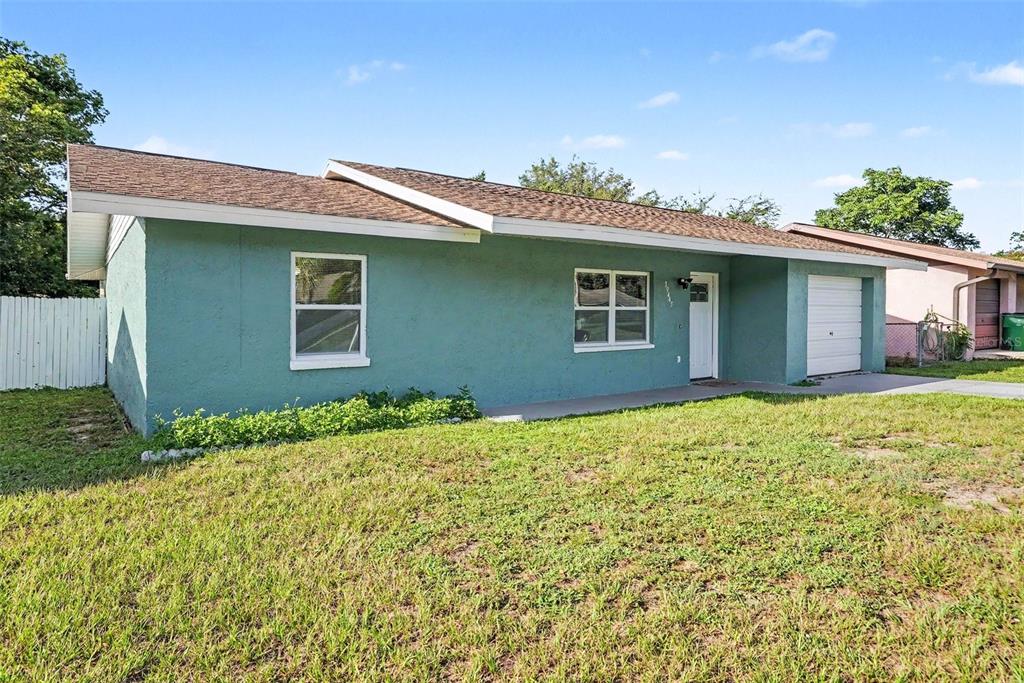 A single-story house with teal stucco siding, a brown shingled roof, and an attached garage — 39443 8TH AVENUE, ZEPHYRHILLS, FL