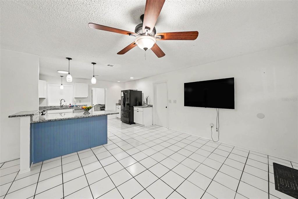 A kitchen with a blue island and white tile floors opens into a living area — 39443 8TH AVENUE, ZEPHYRHILLS, FL