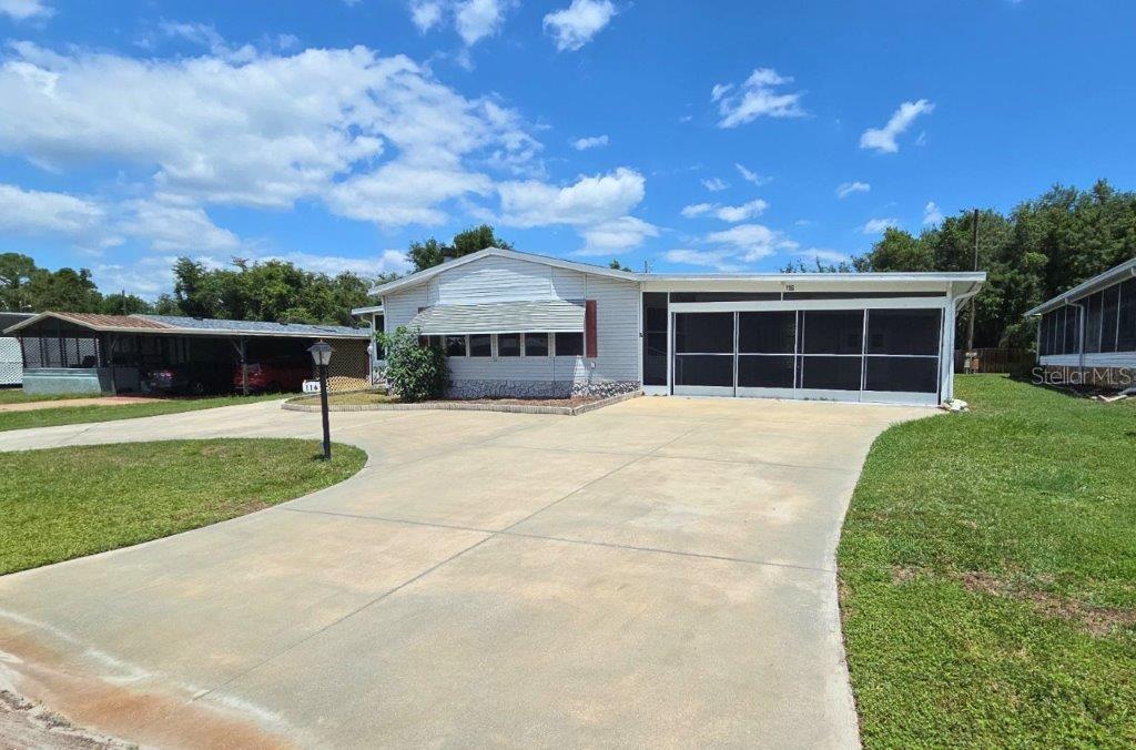 A single-story manufactured home features a large concrete driveway, a carport, and a screened porch — 116 SHER LANE, DEBARY, FL