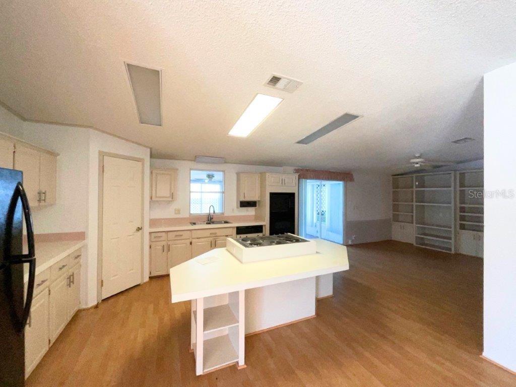 A kitchen with light-colored cabinets, a central island with a cooktop, and wood-look flooring — 116 SHER LANE, DEBARY, FL
