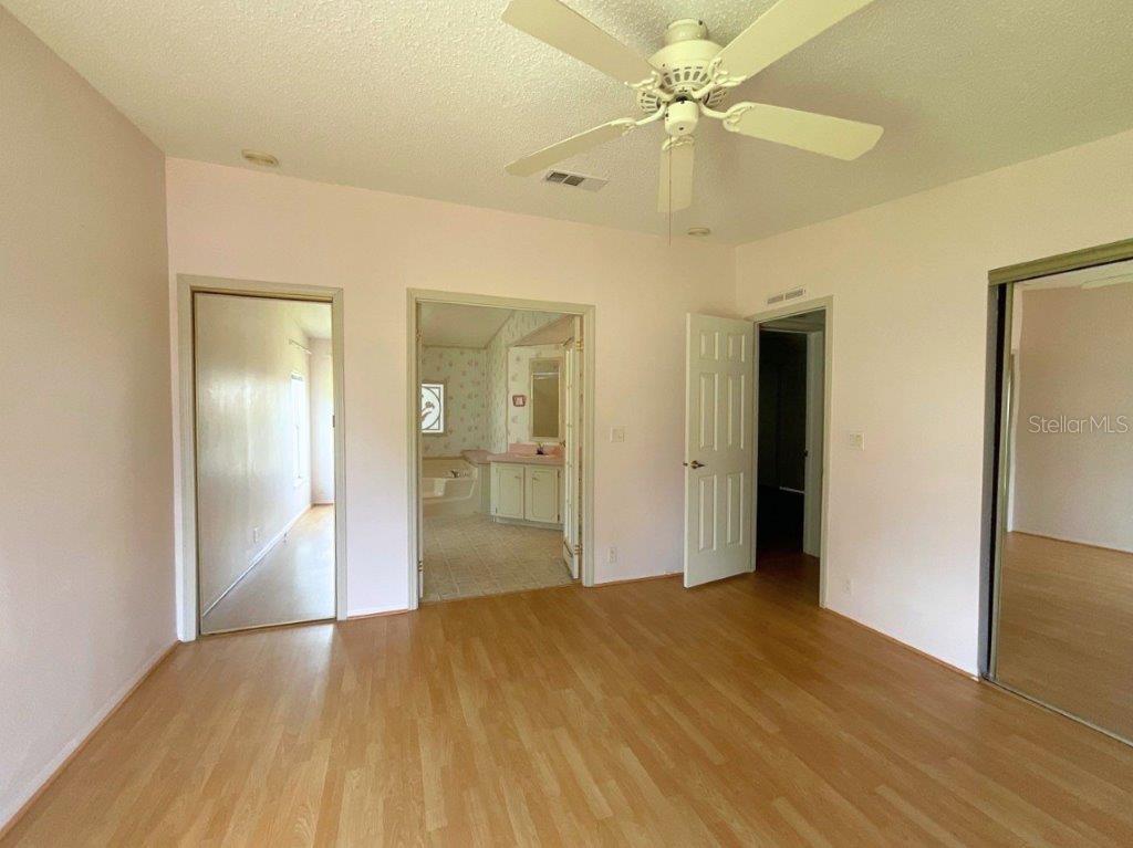 A bedroom with light wood-look flooring, a ceiling fan, and an attached bathroom — 116 SHER LANE, DEBARY, FL