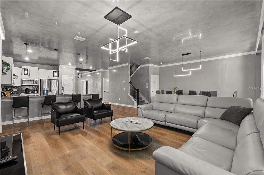 An open-concept living room and kitchen featuring light wood floors and a glossy gray ceiling — 4324 PROLOGUE WAY, KISSIMMEE, FL