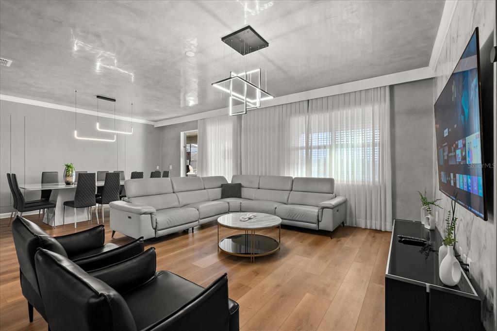 A modern living and dining area features a gray sectional, black chairs, and contemporary lighting — 4324 PROLOGUE WAY, KISSIMMEE, FL