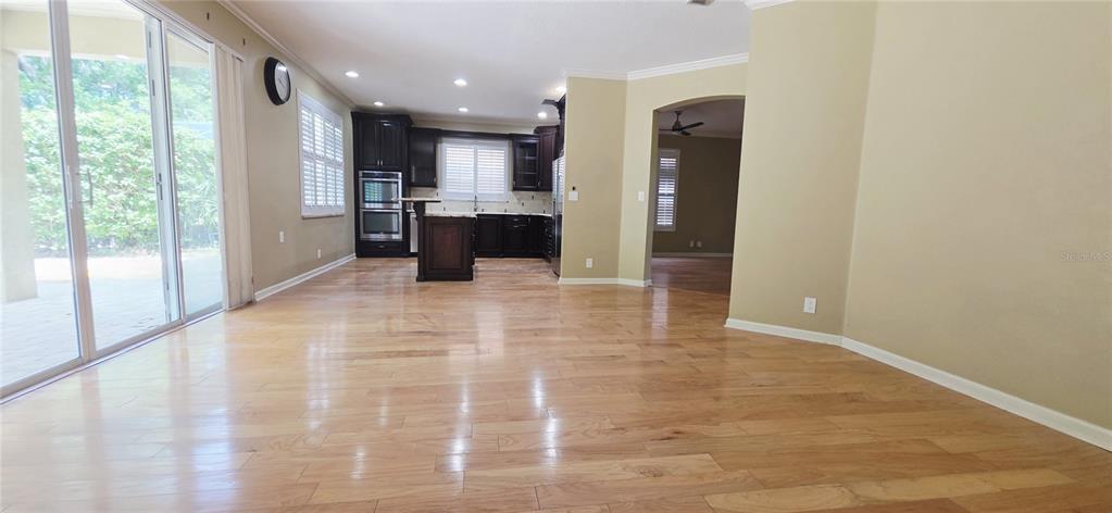 A kitchen with dark cabinets and hardwood floors opens to a living area with sliding doors — 230 W TARRINGTON DRIVE, DELAND, FL