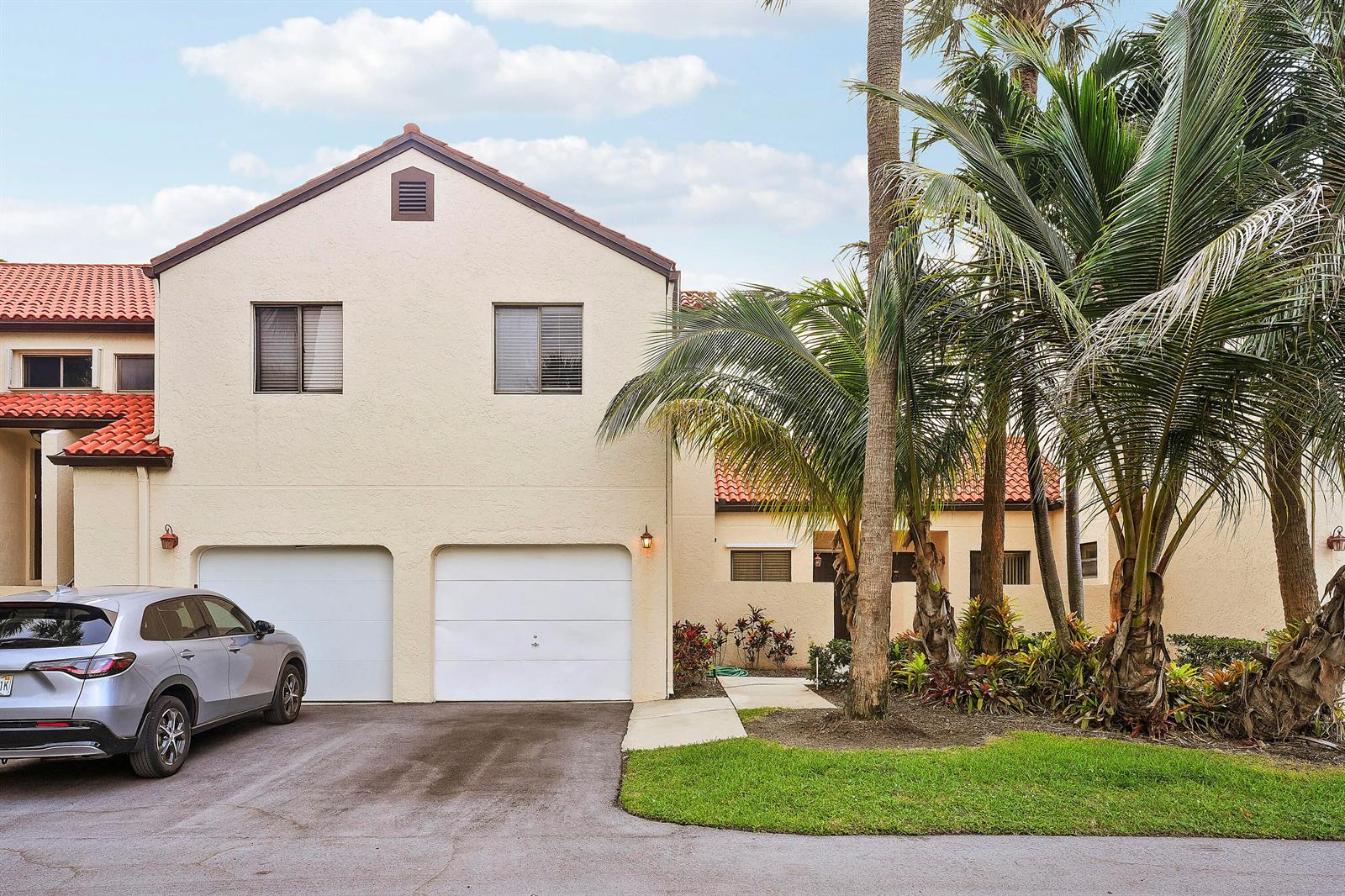 A two-story stucco house with a two-car garage and palm trees in the front yard — 11 Vía De Casas Sur, Boynton Beach FL 33426, BOYNTON BEACH, FL