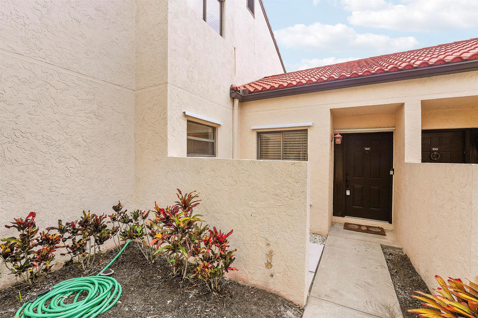 The exterior view shows a tan stucco building with a red tile roof and entryway — 11 Vía De Casas Sur, Boynton Beach FL 33426, BOYNTON BEACH, FL