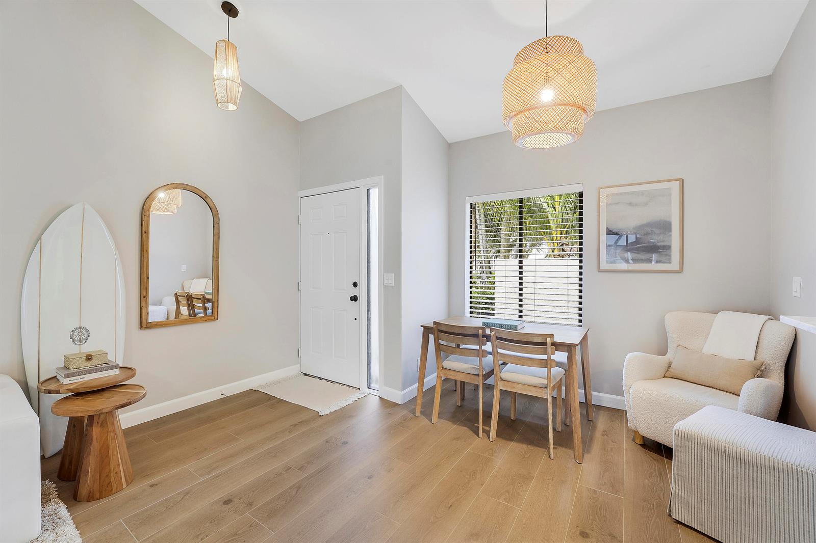A bright dining area features light wood floors, a surfboard, a table, and an armchair — 11 Vía De Casas Sur, Boynton Beach FL 33426, BOYNTON BEACH, FL
