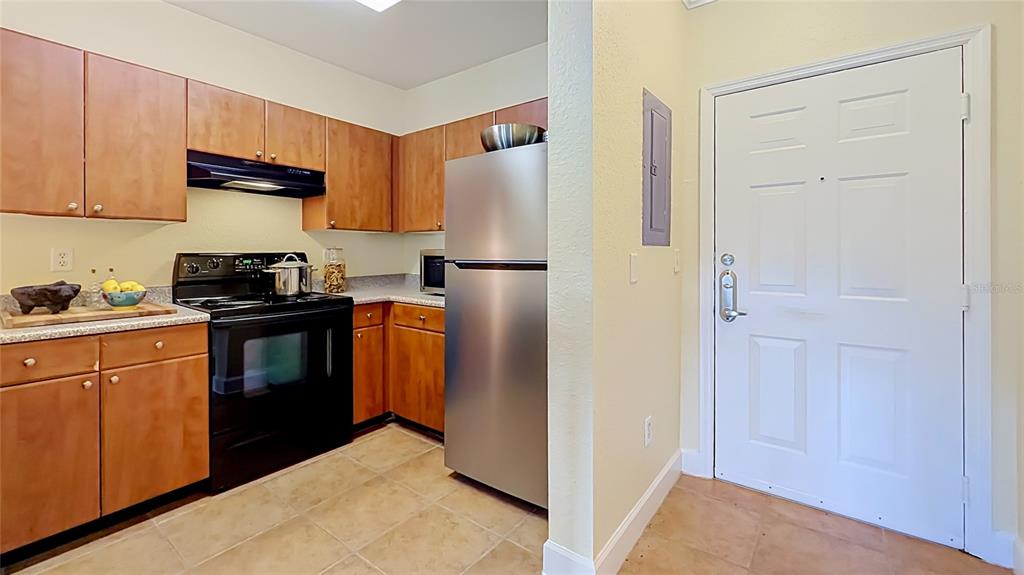 A kitchen features wood cabinets, black appliances, a stainless steel refrigerator, and tile flooring — 202 E SOUTH STREET UNIT 4040, ORLANDO, FL