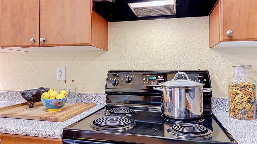 A kitchen features wood cabinets, a black electric stove, and a countertop with pasta — 202 E SOUTH STREET UNIT 4040, ORLANDO, FL