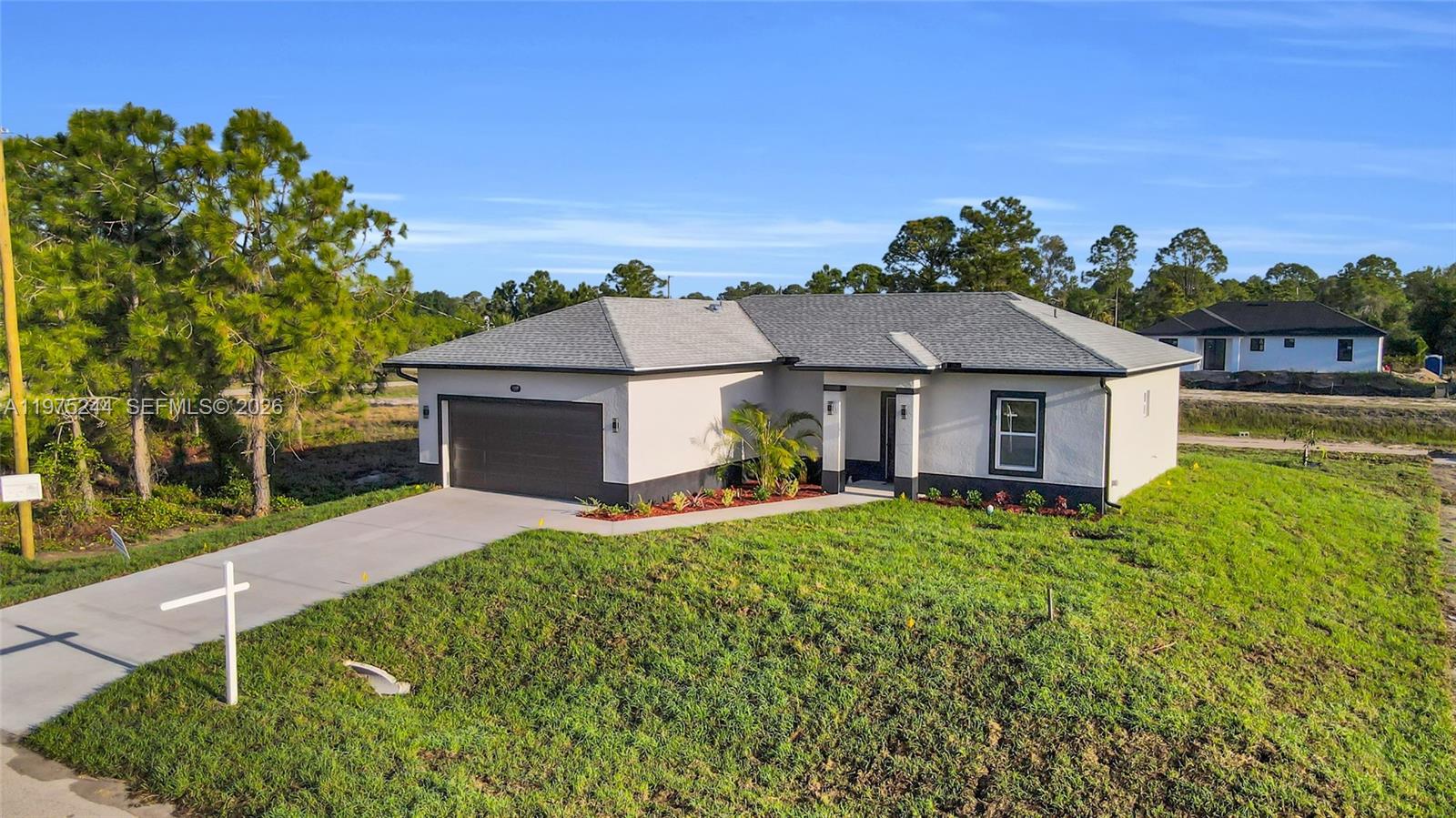 A single-story house with a gray roof, stucco exterior, and attached garage sits on a lawn — 1109 EDGEWOOD ST E, Lehigh Acres FL 33974, LEHIGH ACRES, FL