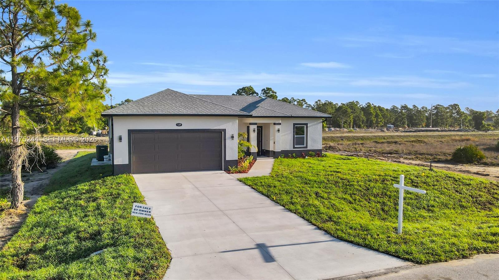 A single-story house with a gray roof, white stucco exterior, and a two-car garage — 1109 EDGEWOOD ST E, Lehigh Acres FL 33974, LEHIGH ACRES, FL