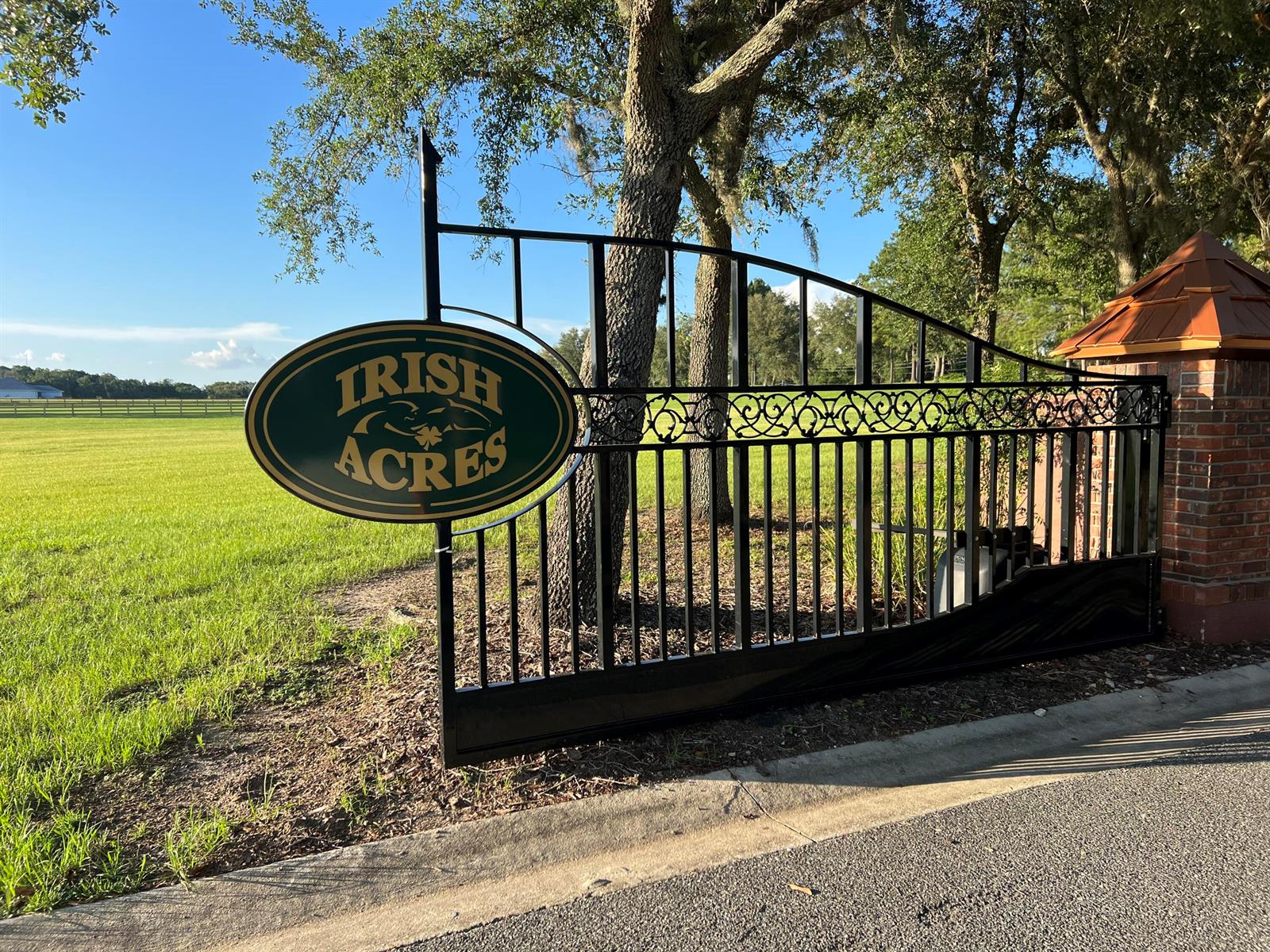 A black metal gate with an oval sign reading Irish Acres stands beside a brick pillar — 000 NW 79th Loop, Ocala FL 34475, OCALA, FL