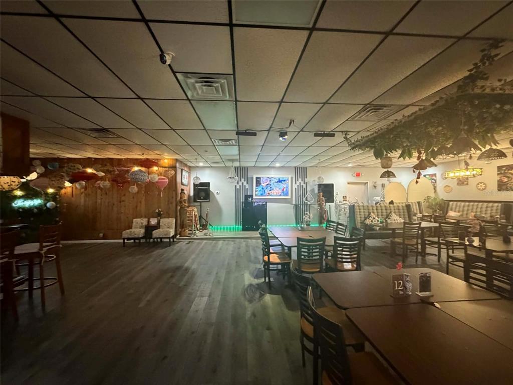 A restaurant interior features wood-paneled walls, a drop ceiling, and tables with chairs — 8256 ULMERTON ROAD, LARGO, FL