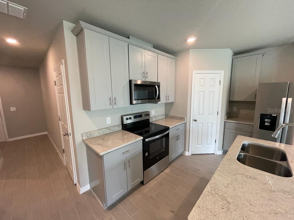A kitchen features gray cabinets, stainless steel appliances, and light-colored countertops — 513 LEGACY LOOP, DAVENPORT, FL