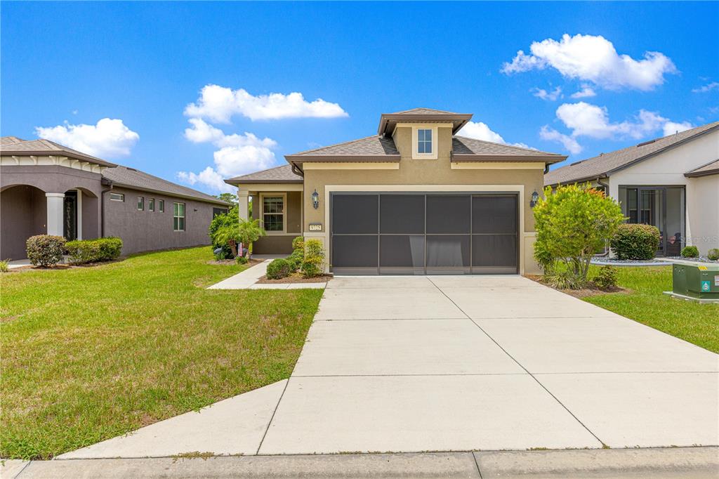 A single-story suburban house features a tan stucco exterior, a screened garage, and a driveway — 9725 SW 63RD LOOP, OCALA, FL