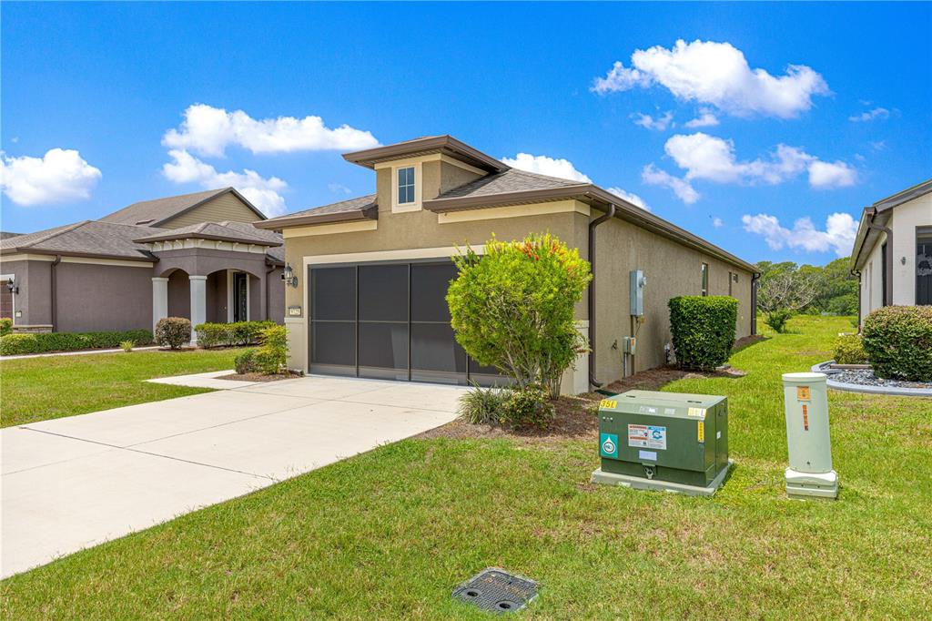 A tan single-story house with a screened garage door sits on a grassy lot — 9725 SW 63RD LOOP, OCALA, FL