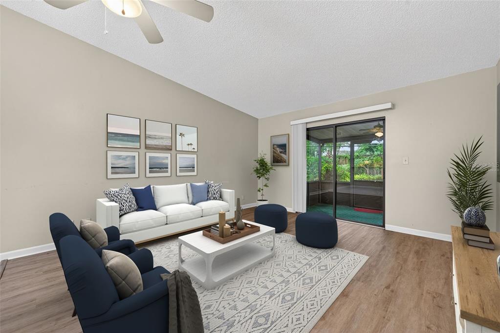 This living room features a white sofa, blue armchairs, a coffee table, and sliding glass doors — 39650 US HIGHWAY 19 N UNIT 565, TARPON SPRINGS, FL