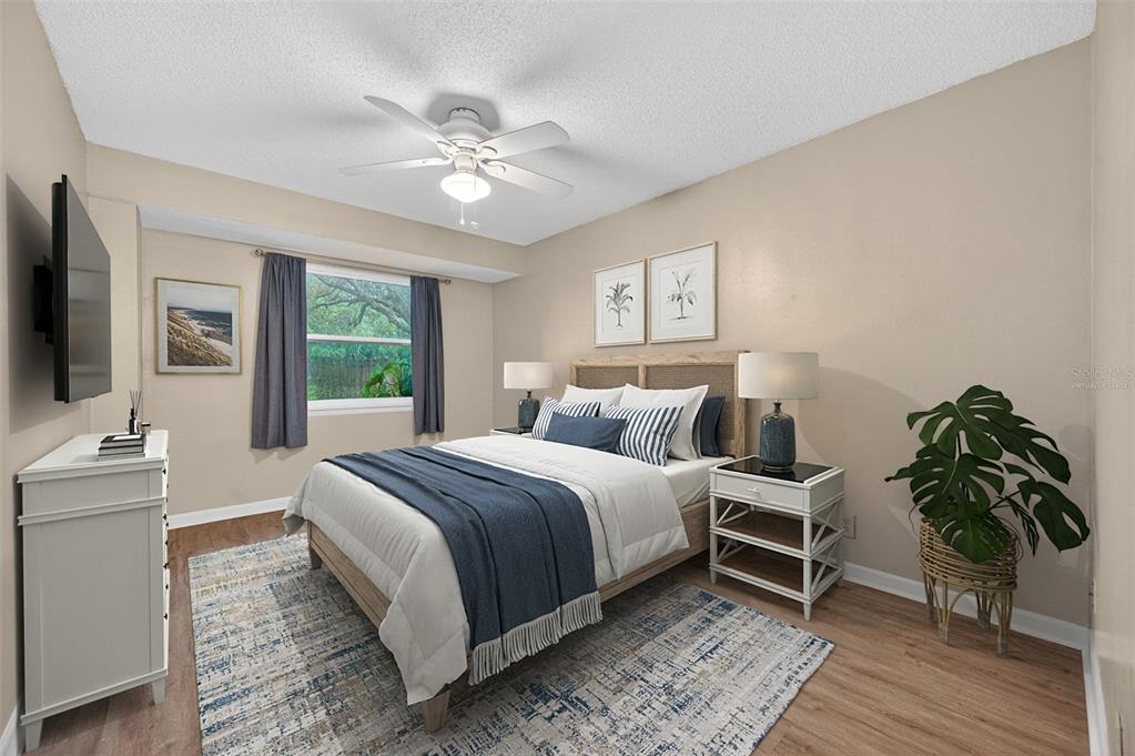 A bedroom features a bed with blue bedding, a ceiling fan, and a white dresser — 39650 US HIGHWAY 19 N UNIT 565, TARPON SPRINGS, FL