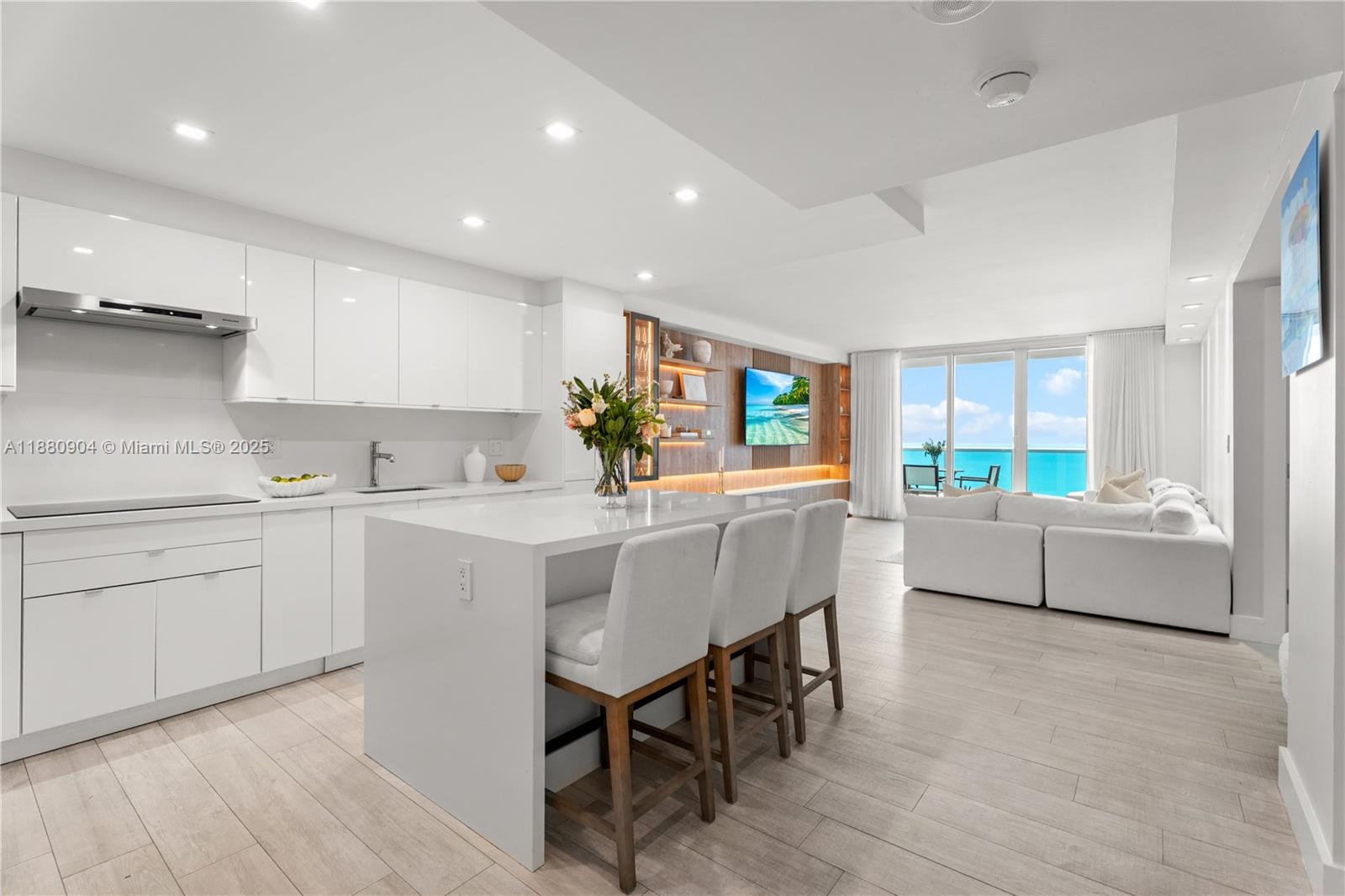 A modern open-concept kitchen and living area features white cabinetry, a central island, and ocean views — 2301 Collins Ave # 24, Miami Beach FL 33139, MIAMI BEACH, FL