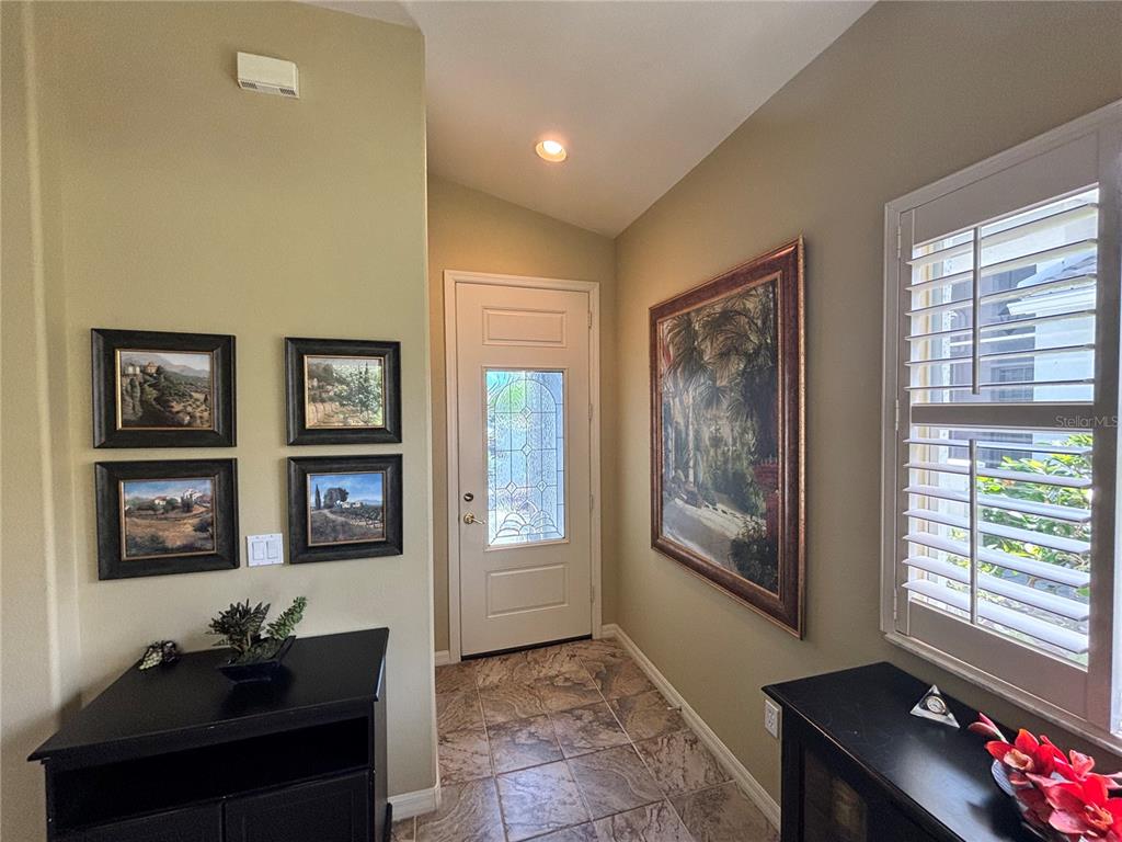 An entryway features tile flooring, a white front door with glass, and framed wall art — 310 RECLINATA CIRCLE, VENICE, FL