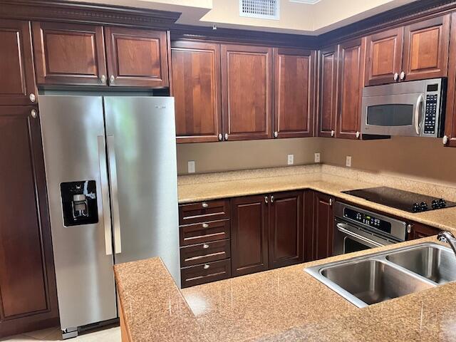 A kitchen features dark wood cabinetry, stainless steel appliances, and speckled granite countertops — 4 Renaissance Way # 302, Boynton Beach FL 33426, BOYNTON BEACH, FL