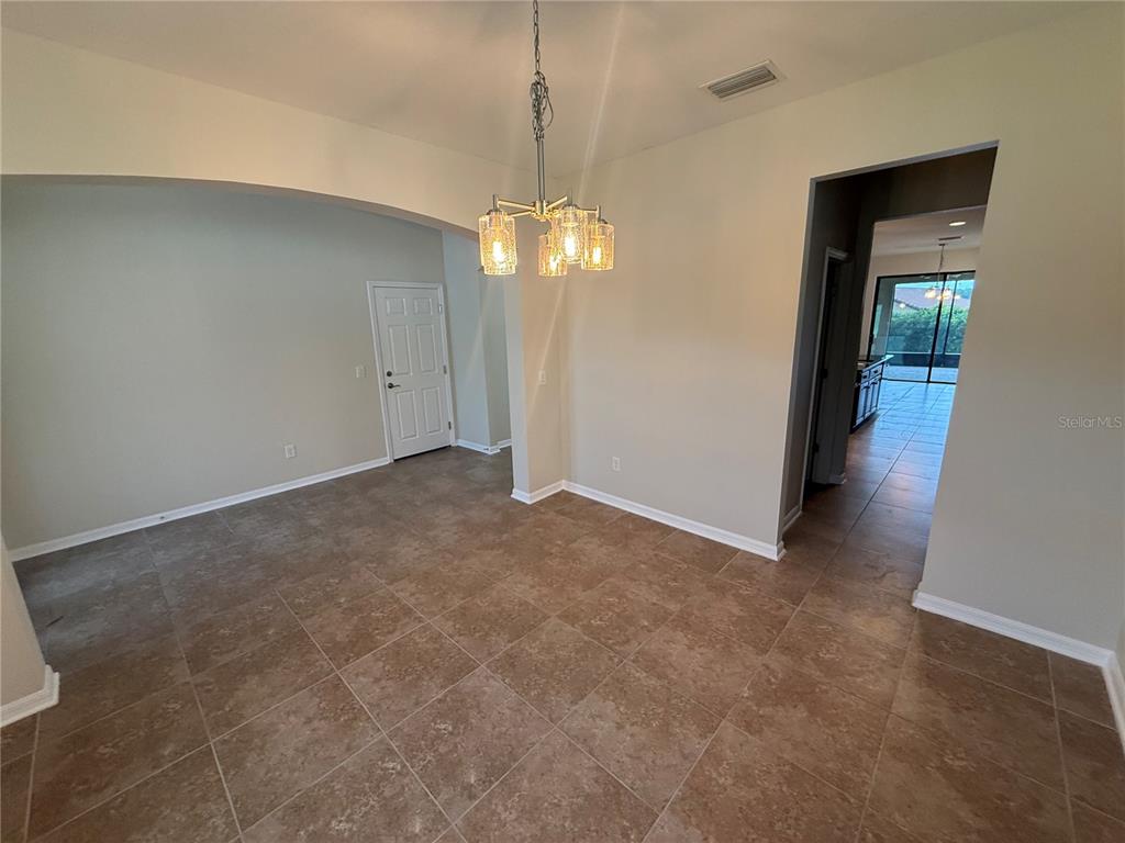 A dining area with tile flooring, a hanging chandelier, and an arched entryway — 3969 AQUILLA DRIVE, LAKELAND, FL