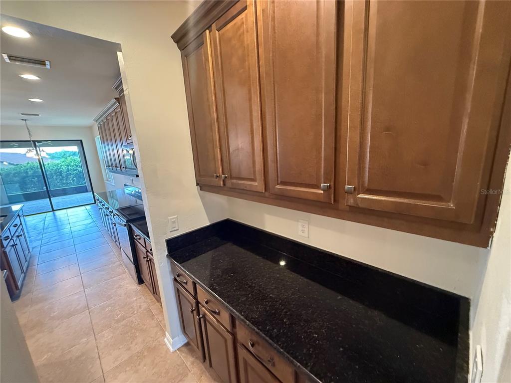 A kitchen features dark wood cabinets, black granite countertops, and tile flooring — 3969 AQUILLA DRIVE, LAKELAND, FL