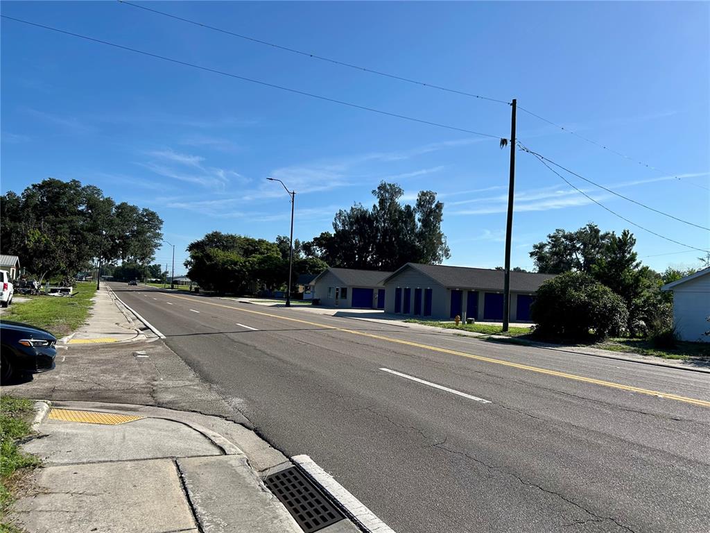 A street view shows a paved road, a sidewalk, and a storage facility with blue doors — 109 ORANGE STREET, BOWLING GREEN, FL