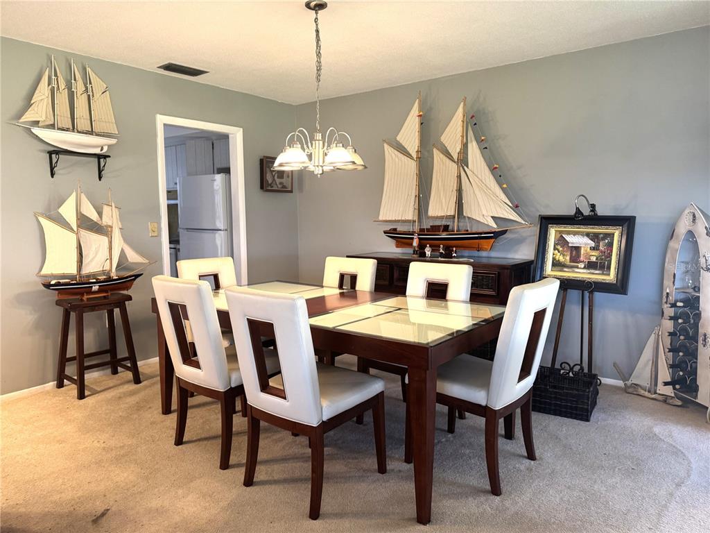 A dining room features a glass-topped table, white chairs, and several model ship decorations — 2571 RIVERBLUFF PARKWAY UNIT V158, SARASOTA, FL