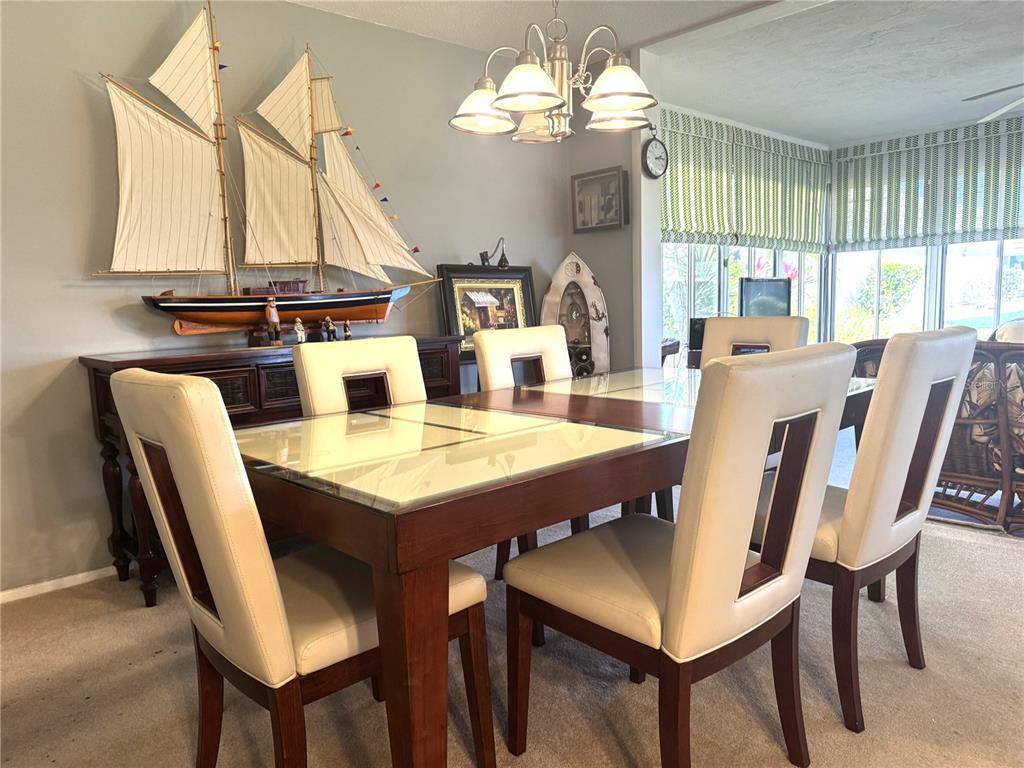 A dining room features a wooden table with a glass top, six chairs, and a model ship — 2571 RIVERBLUFF PARKWAY UNIT V158, SARASOTA, FL