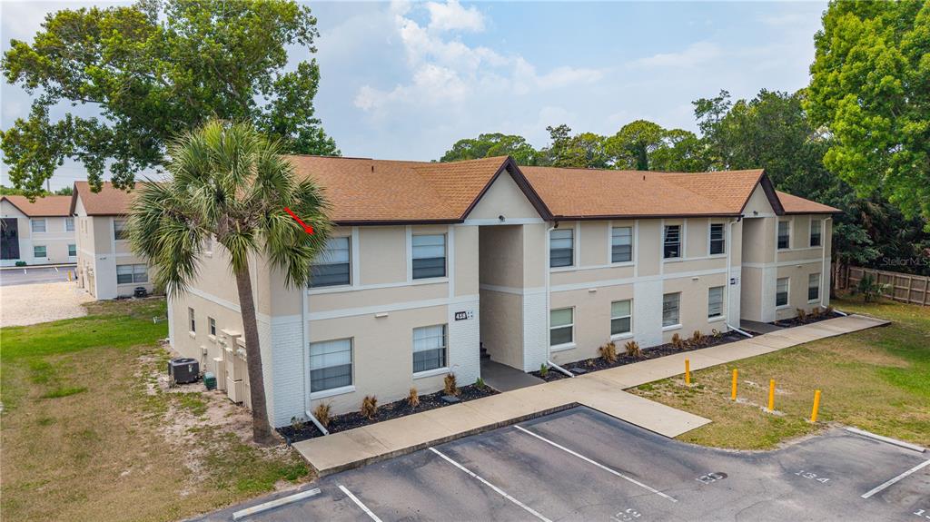 An exterior view of a two-story apartment building with beige stucco and a brown roof — 418 BANANA CAY DRIVE UNIT E, DAYTONA BEACH, FL