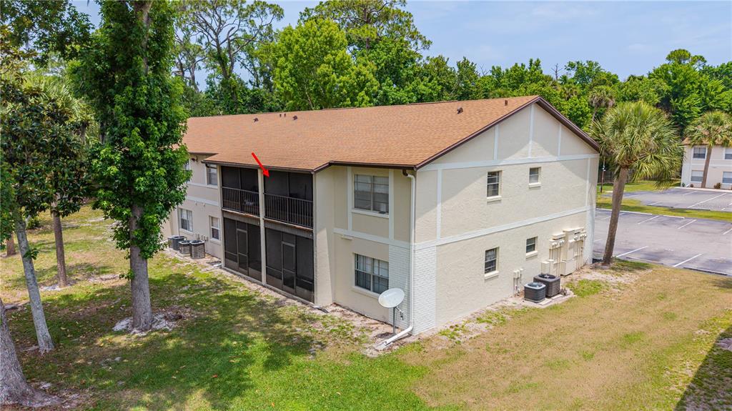 An exterior view of a two-story apartment building with screened-in balconies and a parking lot — 418 BANANA CAY DRIVE UNIT E, DAYTONA BEACH, FL