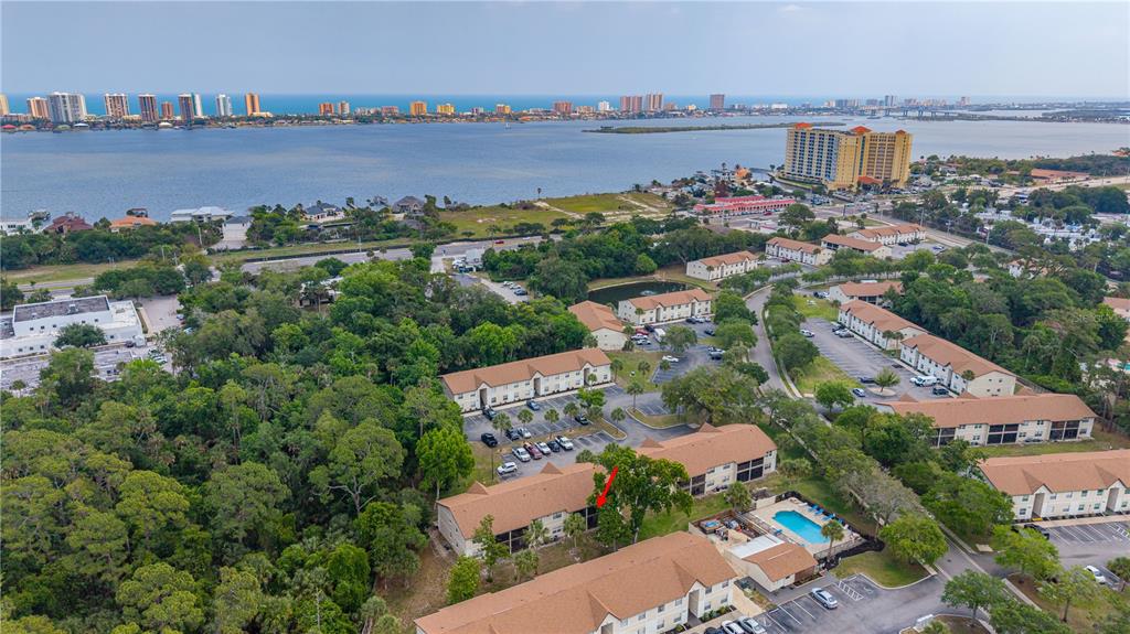 An aerial view shows a multi-story apartment complex with a pool and surrounding trees — 418 BANANA CAY DRIVE UNIT E, DAYTONA BEACH, FL