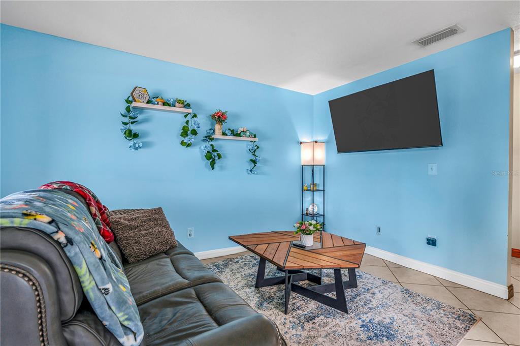 A living room features light blue walls, a dark sofa, and a geometric wood coffee table — 418 BANANA CAY DRIVE UNIT E, DAYTONA BEACH, FL