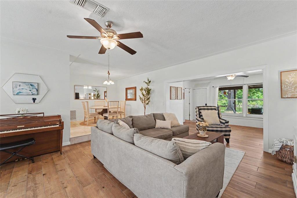 A living room with a gray sectional sofa, wood flooring, and an adjacent dining area — 8879 LAKEWOOD DRIVE, SEMINOLE, FL
