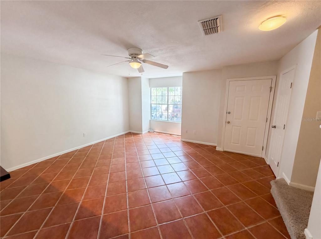 An empty room features terracotta-colored tile flooring, a ceiling fan, and a white entry door — 510 GREEN SPRING CIRCLE, WINTER SPRINGS, FL