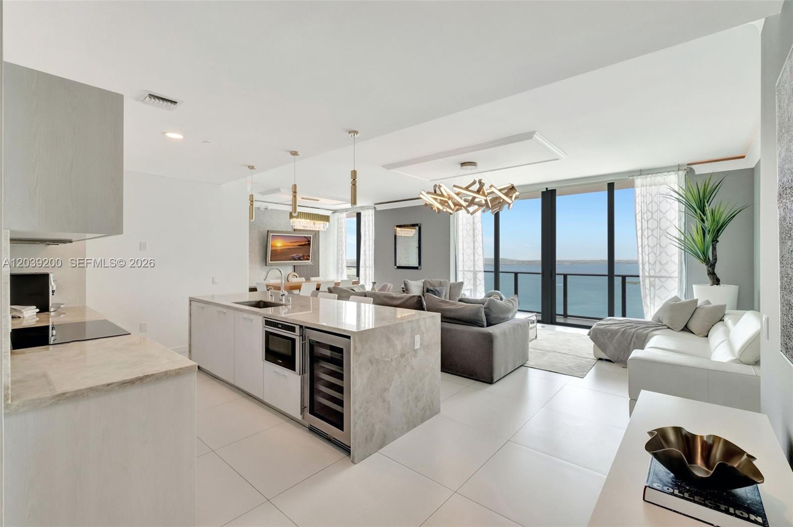 A modern open-concept kitchen and living area features a stone island and ocean views — 501 NE 31st St, Miami FL 33137, MIAMI, FL