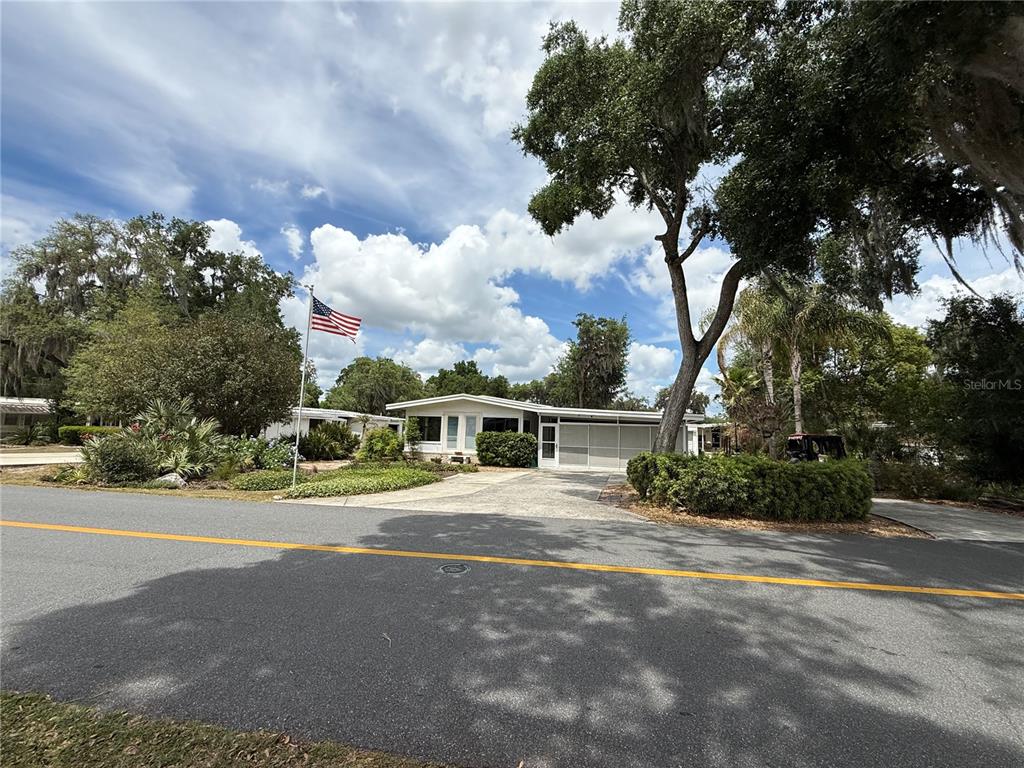A single-story house with a white exterior, a concrete driveway, and an American flag — 9 S BOBWHITE ROAD, WILDWOOD, FL