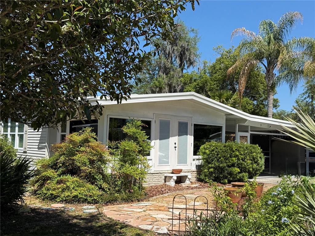 A white mobile home with a stone patio and double glass doors under a roof — 9 S BOBWHITE ROAD, WILDWOOD, FL