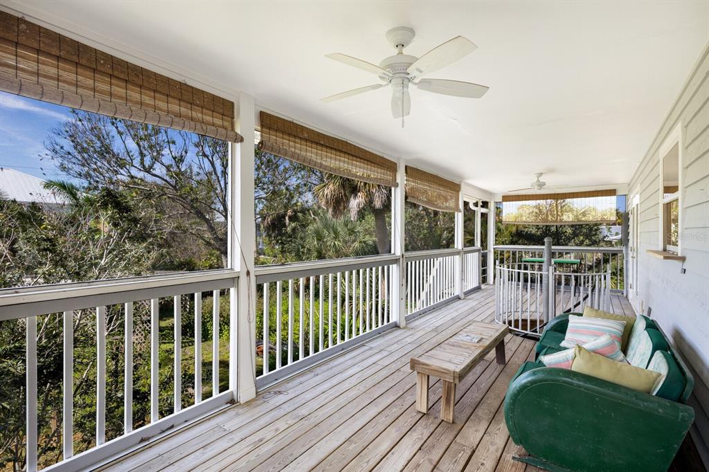 A covered wooden deck features a ceiling fan, white railings, and a green outdoor sofa — 362 BAILY STREET, BOCA GRANDE, FL