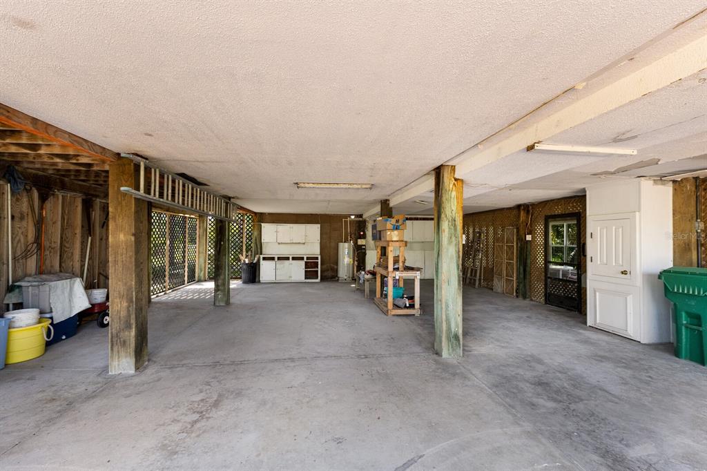 A large, open-air concrete carport features wooden support posts, storage cabinets, and a utility area — 362 BAILY STREET, BOCA GRANDE, FL