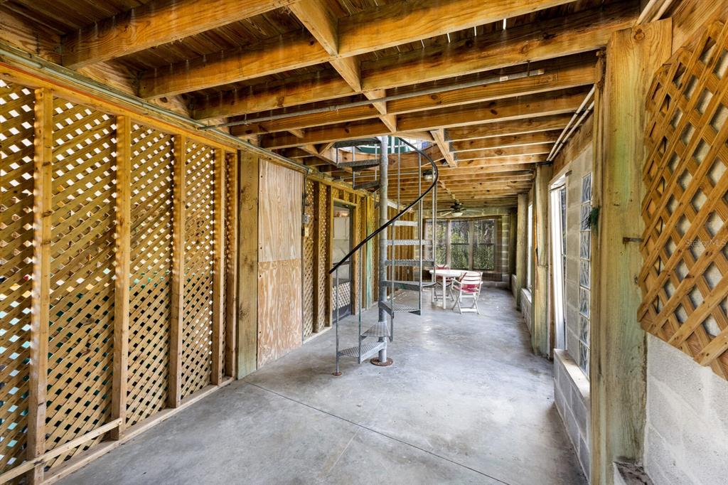A covered concrete patio features a metal spiral staircase and wooden lattice wall panels — 362 BAILY STREET, BOCA GRANDE, FL