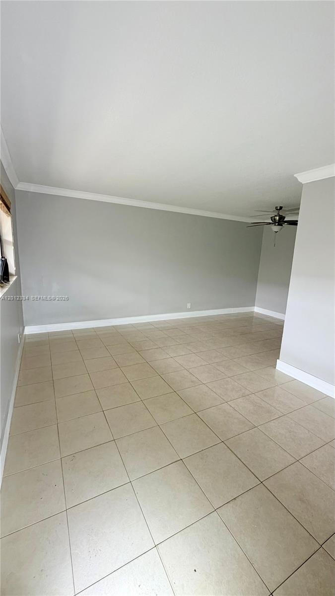 An empty room features light gray walls, beige tile flooring, and a ceiling fan — 581 Kathy Ln # D, Margate FL 33068, MARGATE, FL