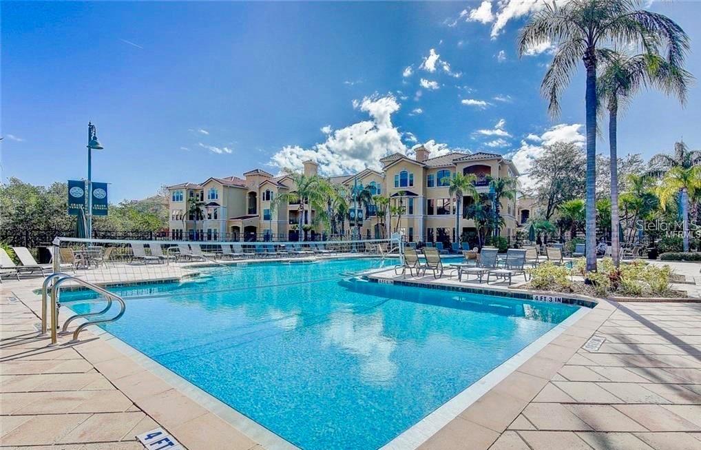 A swimming pool with a volleyball net sits in front of a multi-story apartment building — 2713 VIA MURANO UNIT 232, CLEARWATER, FL
