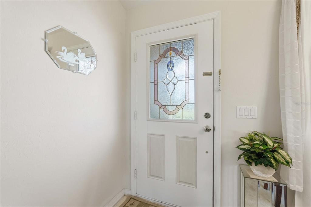 An entryway features a white front door with a decorative glass insert and a wall mirror — 4112 10TH STREET W, LEHIGH ACRES, FL