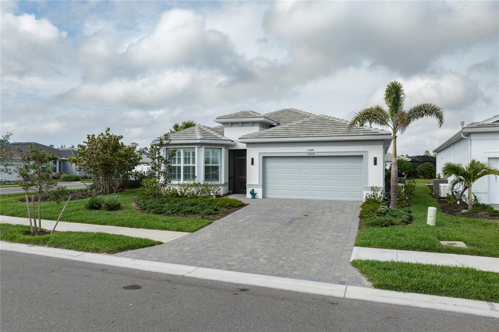 A single-story house with a paved driveway, a two-car garage, and a palm tree — 9978 BRIGHT WATER DRIVE, ENGLEWOOD, FL