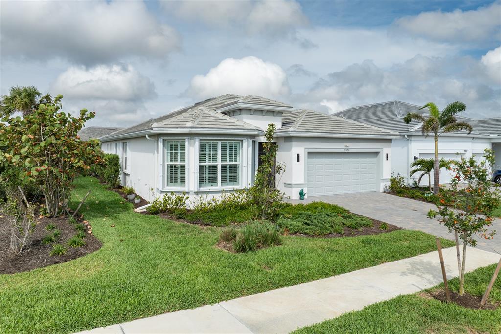 A single-story house with a gray tile roof, white stucco exterior, and a two-car garage — 9978 BRIGHT WATER DRIVE, ENGLEWOOD, FL