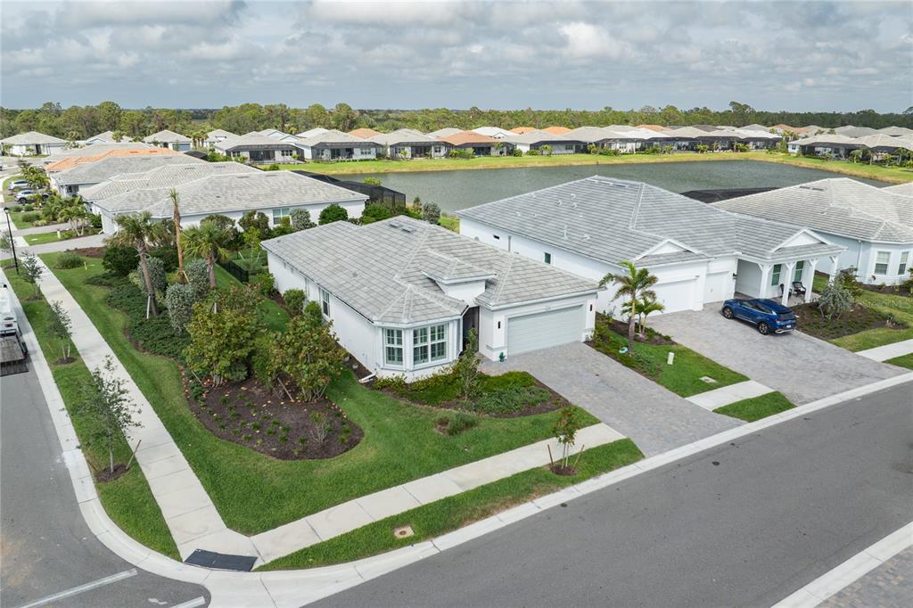 An aerial view shows a suburban house with a gray tiled roof and driveway — 9978 BRIGHT WATER DRIVE, ENGLEWOOD, FL